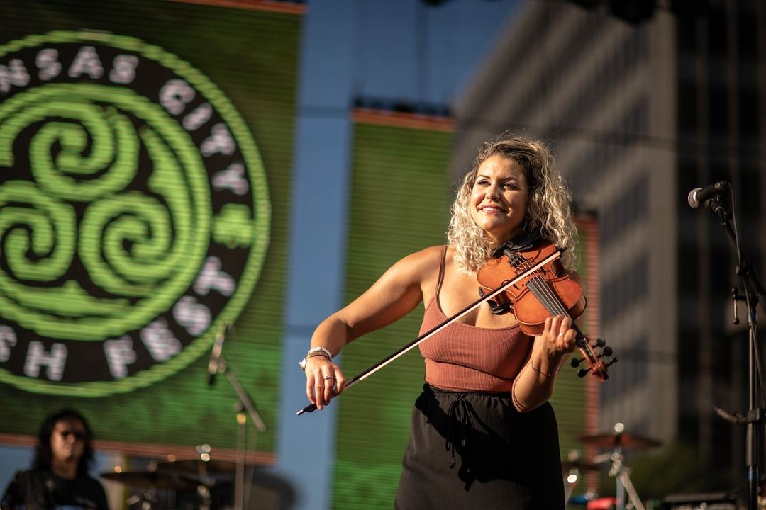 A muscian strumming a violin while on stage at a KCMO music festival. @crowncenter