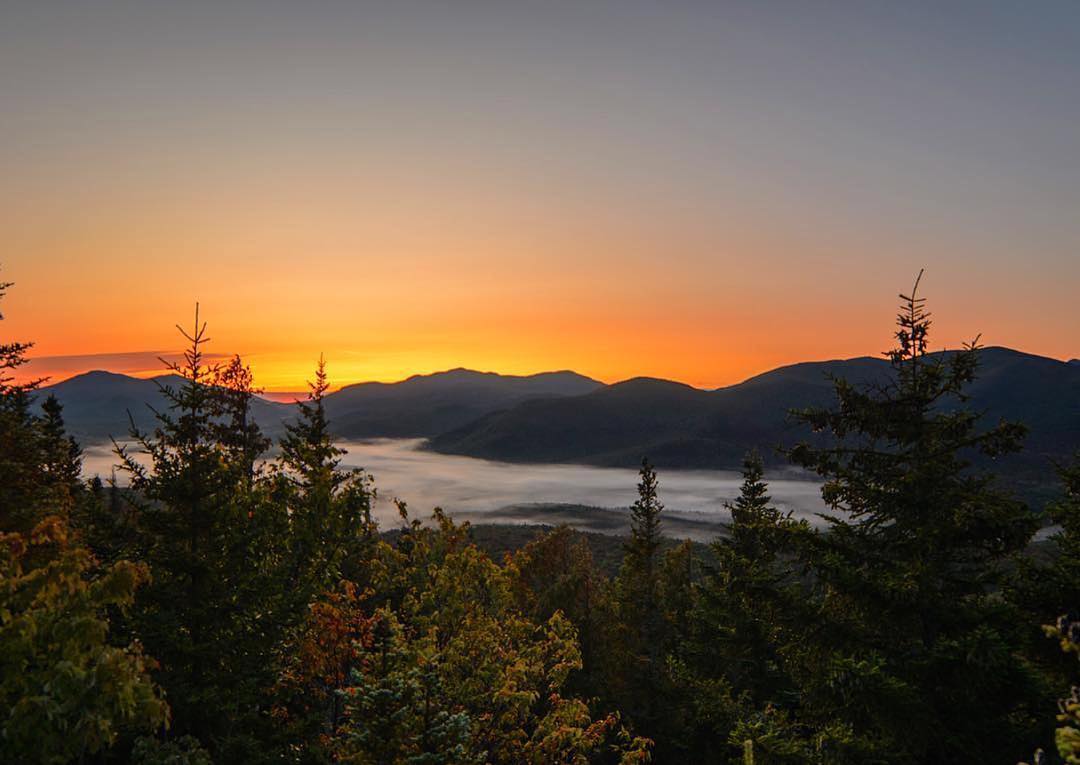 Tall green trees and mountains during sunset at Adirondack Park, NY. Photo by Instagram user @patbly