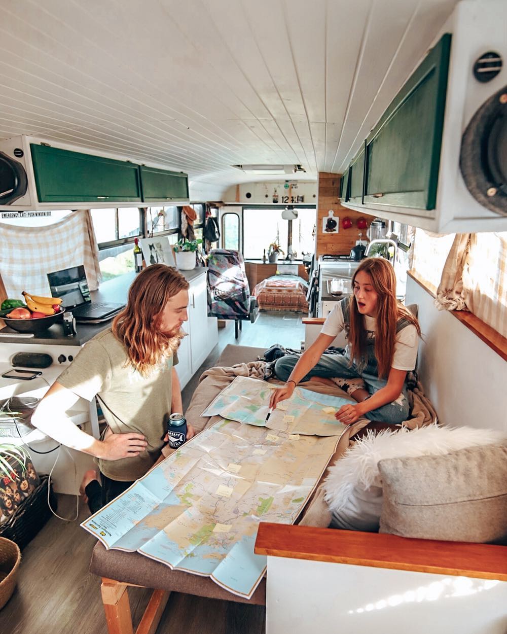 Couple planning a trip on a map in their van. Photo by Instagram user @thejahbus