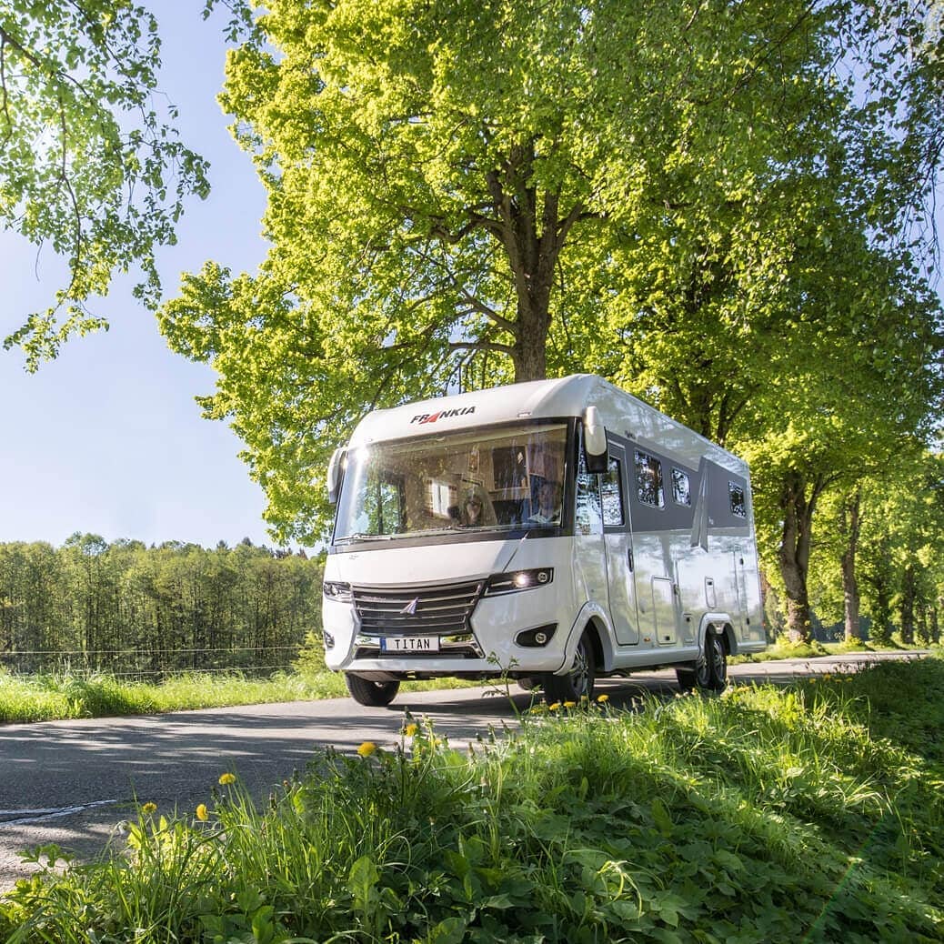 White camper driving by trees. Photo by Instagram user @camprest_com