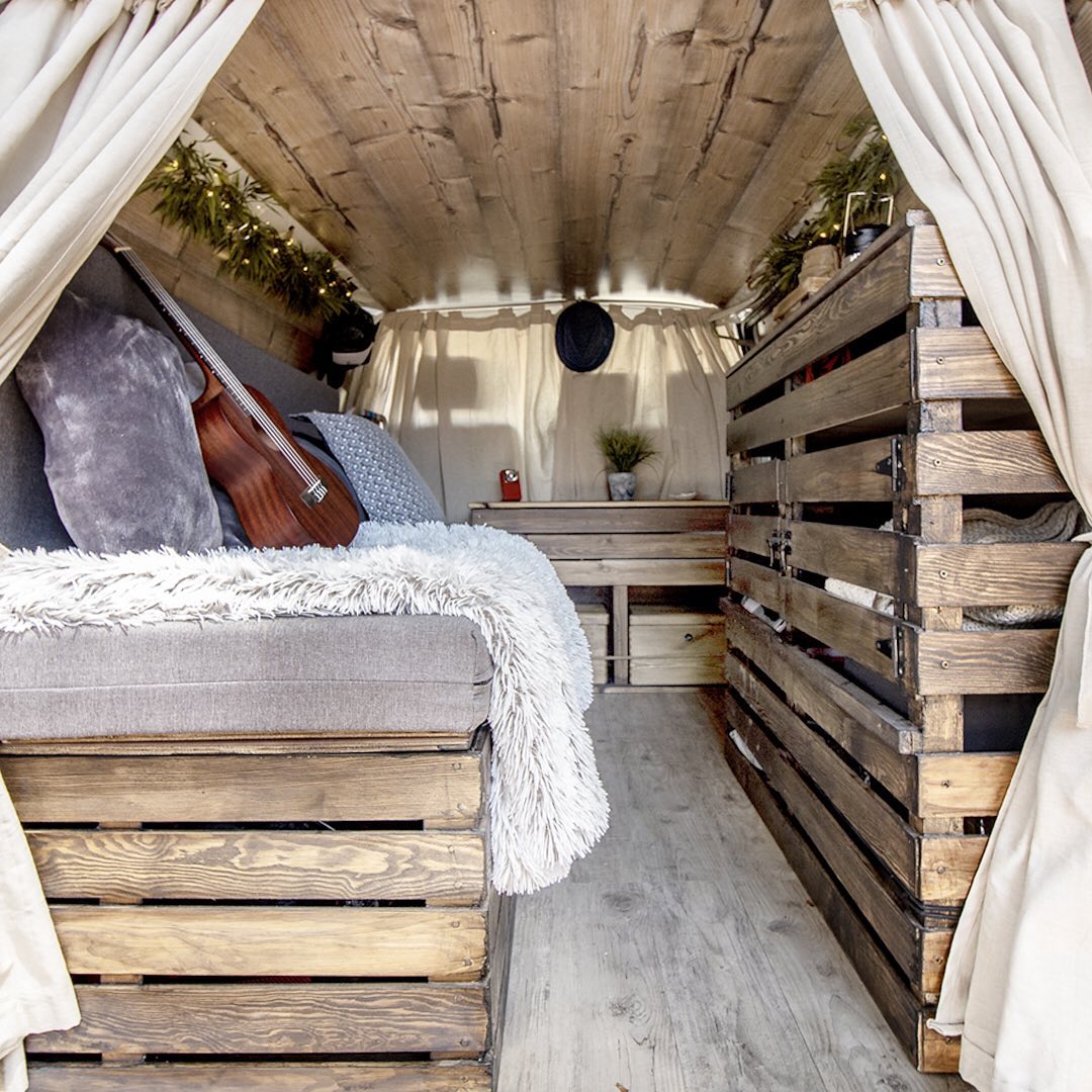 Back of van with wood bed frame and white curtains. Photo by Instagram user @dannyfreediver