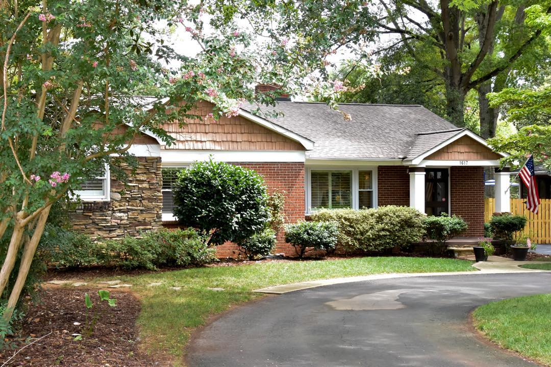 Red brick and stone house with white pillars shaded by trees in Freedom Park, Charlotte. Photo by Instagram user @joannaenten