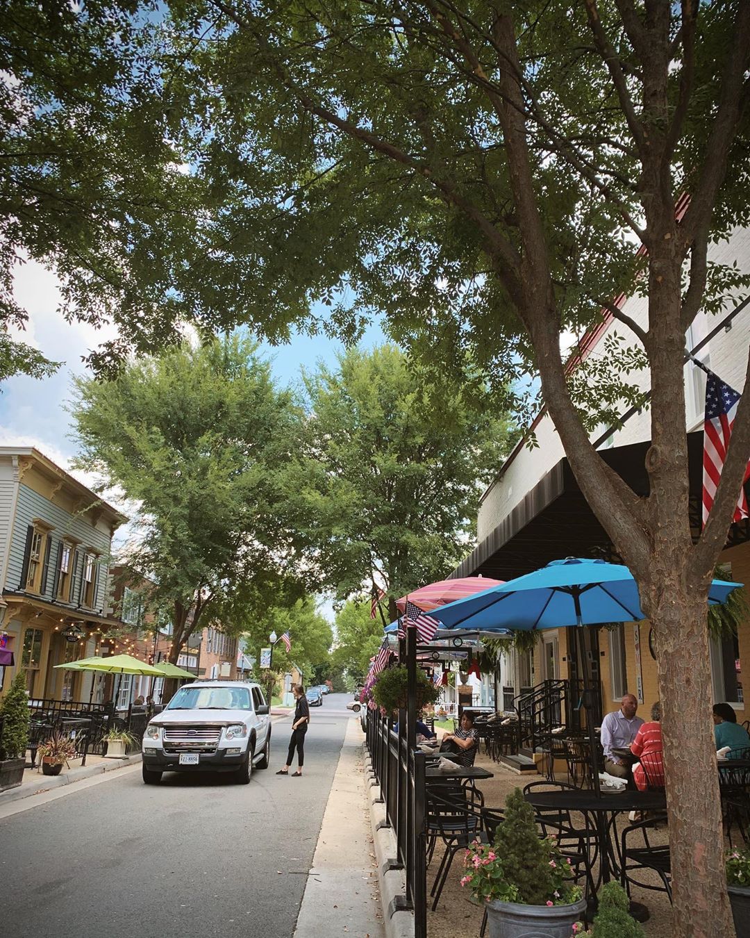 Street view of restaurants and colorful umbrellas in Old Town Manassas, VA. Photo by Instagram user @makeupdelight
