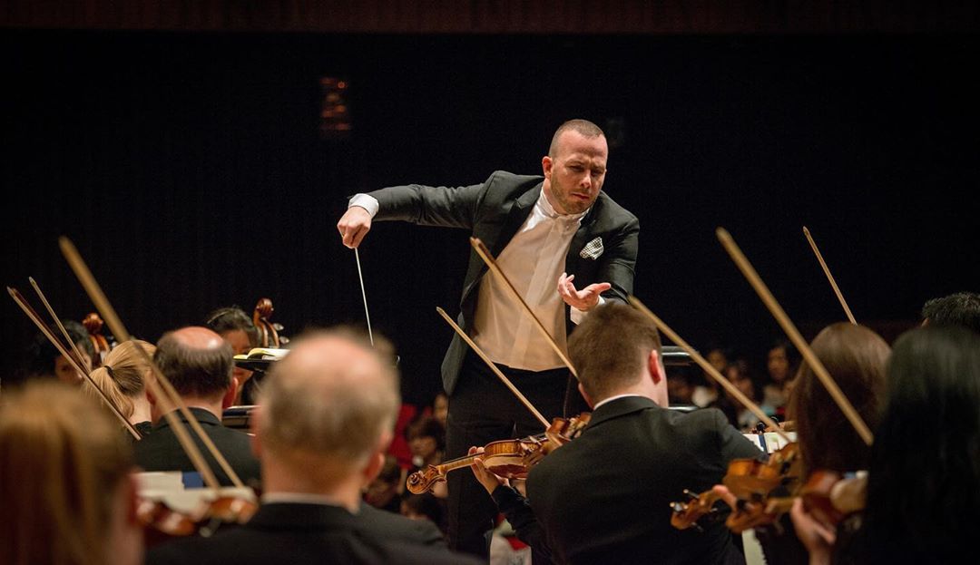 Maestro leading an orchestra performance. Photo by Instagram user @philorch