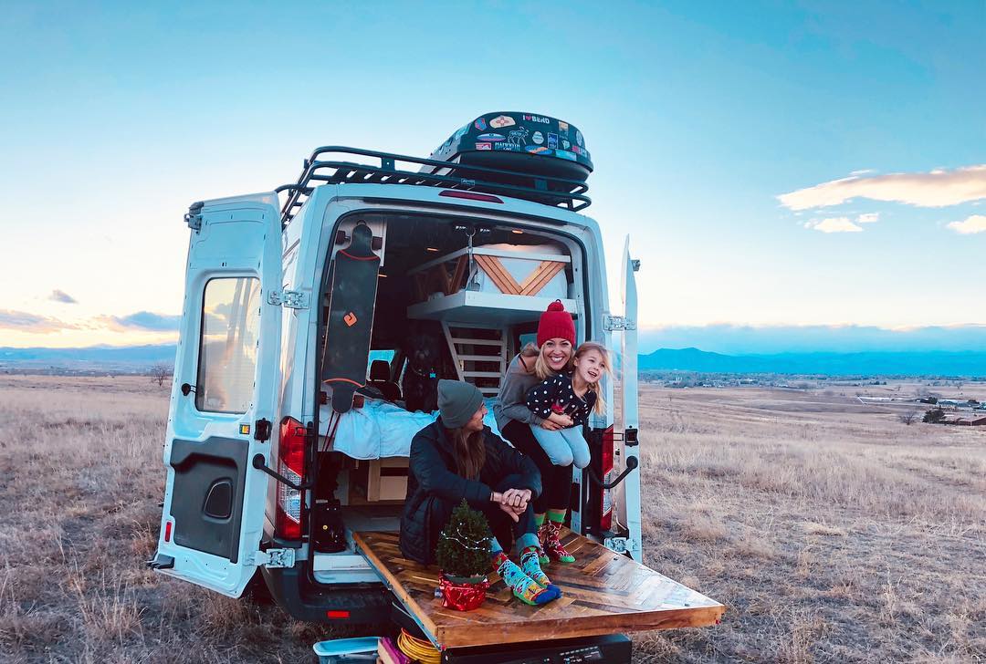 Family sitting on a pullout deck on a van. Photo by Instagram user @fitetravels