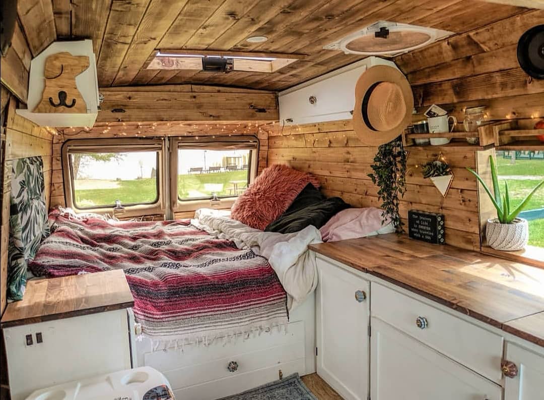 Van with all paneling on the inside with white cabinets. Photo by Instagram user @doratheexplorervan