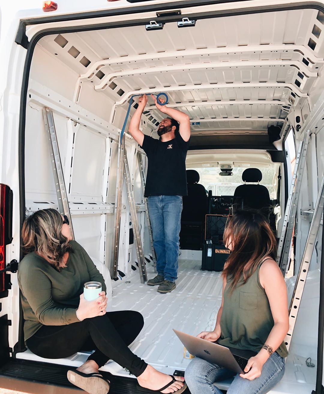 Man and two women fixing the inside of a van. Photo by Instagram user @losthiway_customs