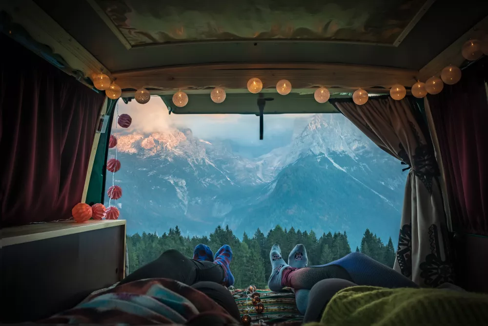 Back of van trunk with string lights by the mountains.