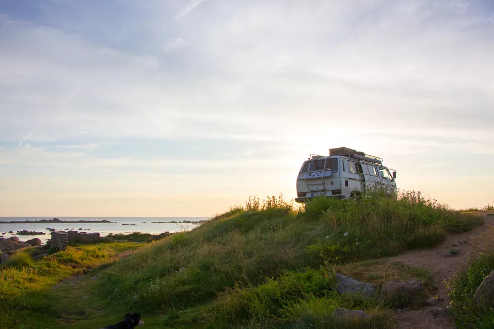 Van on a grassy hill at sunset