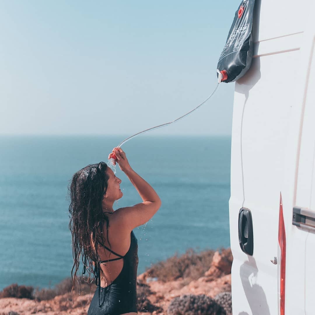Girl showering in her swimsuit outside of her van. Photo by Instagram user @salty.roamers