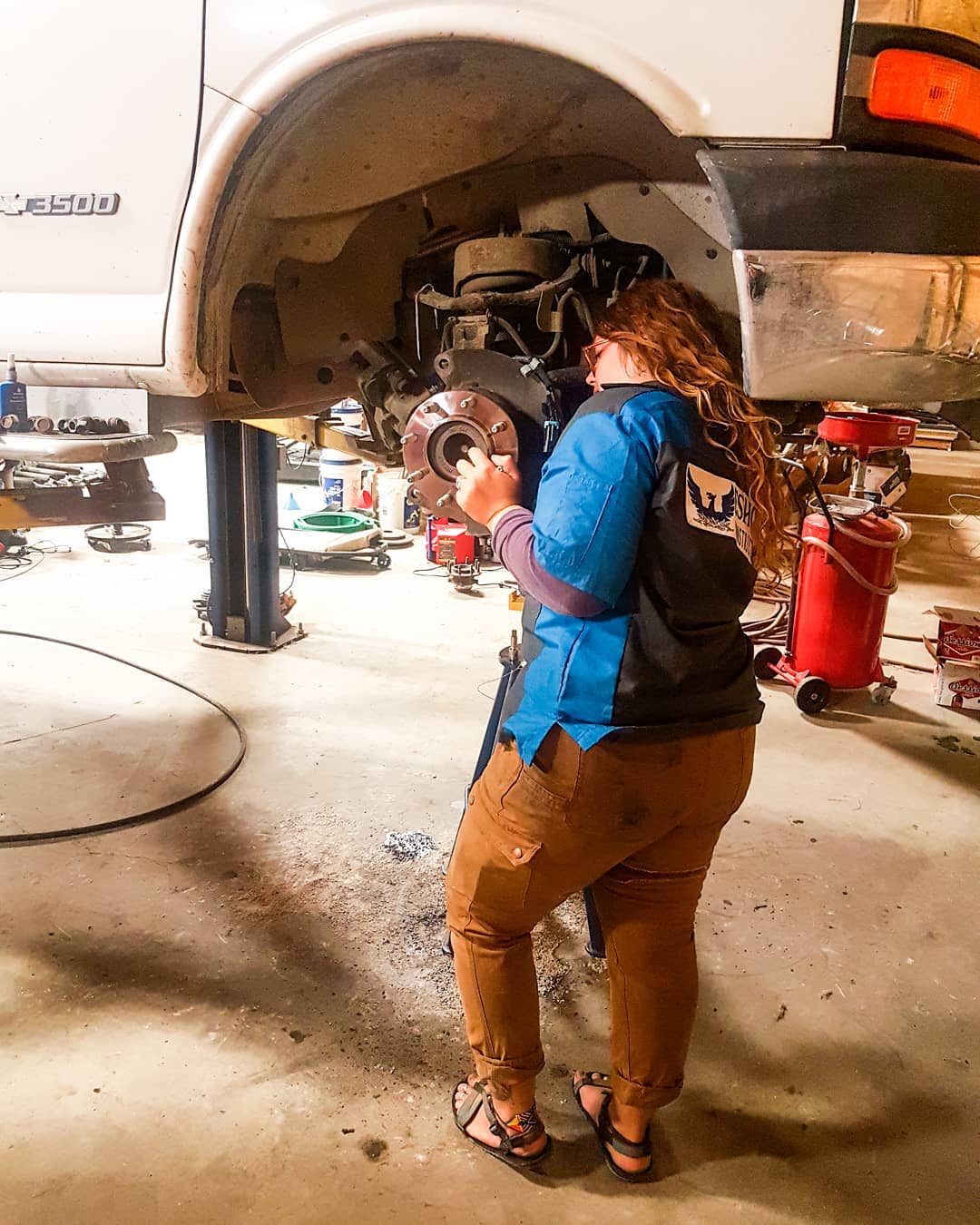 Girl fixing the tire on her van. Photo by Instagram user @practicalparadise