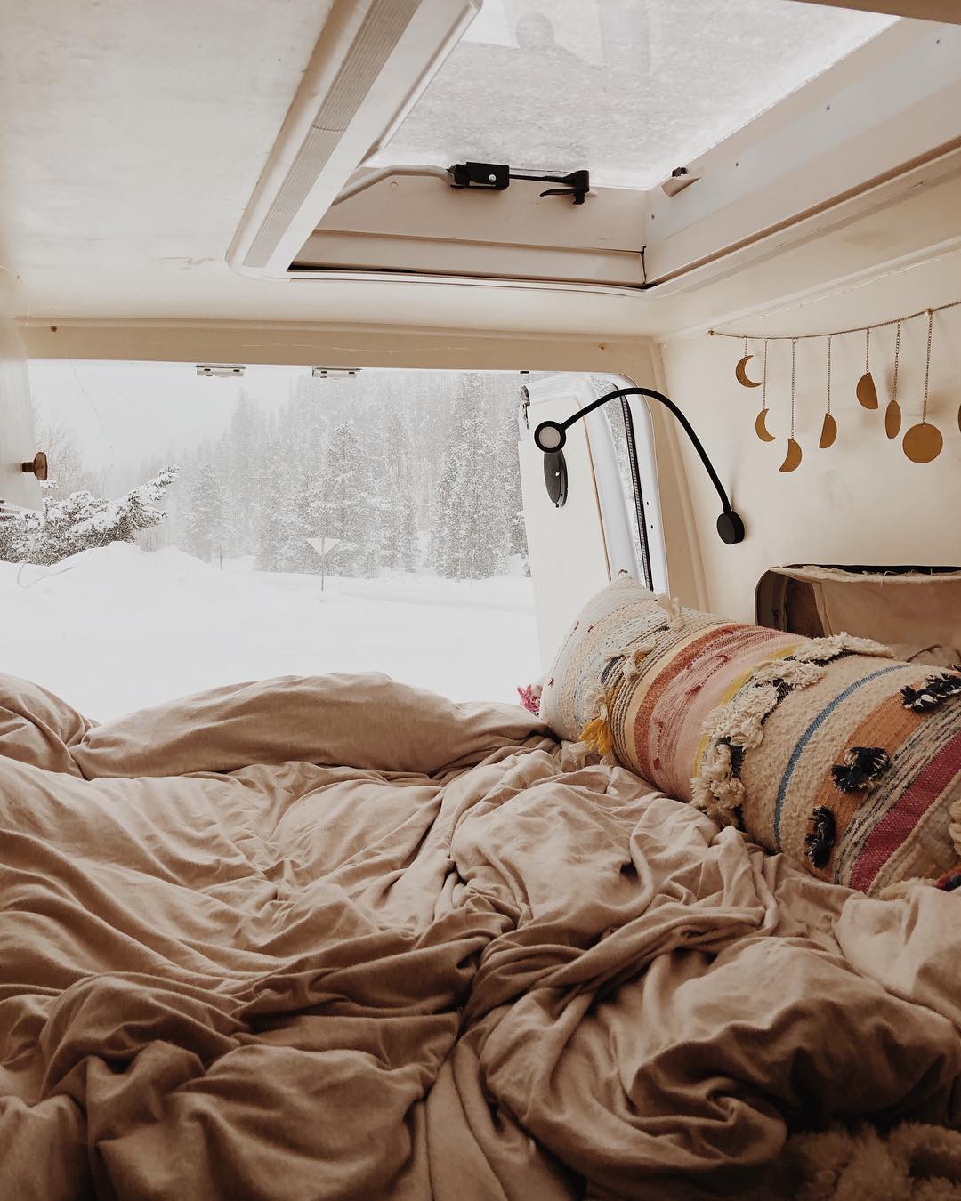 Van bed with a snow storm in the background. Photo by Instagram user @dynamoultima