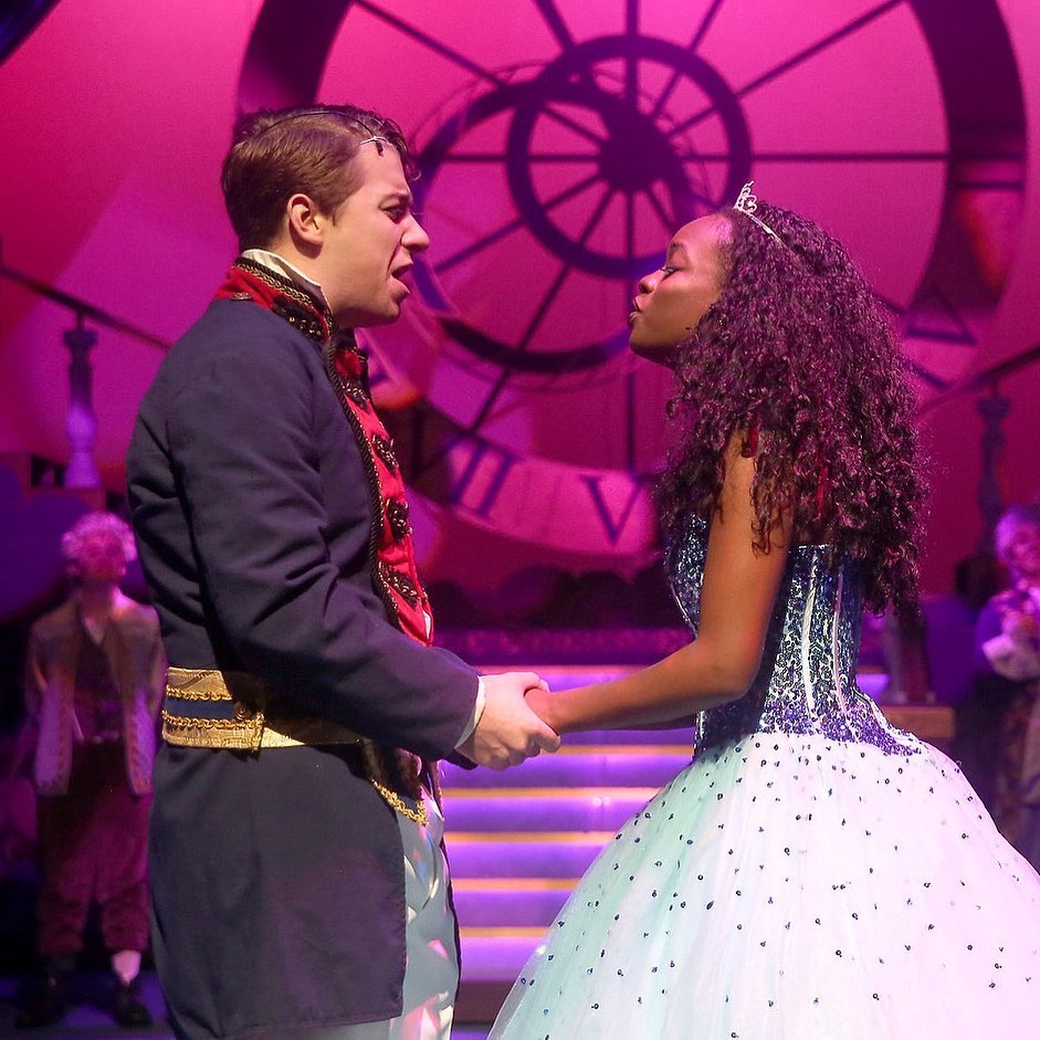 Two actors stand on stage while holding hands. Photo by Instagram user @bhamchildrenstheatre.