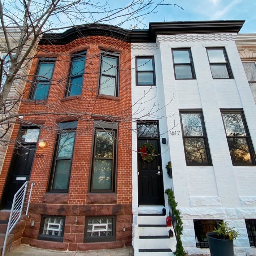 Two modern row houses with tall thin windows and subtle brick detailing alone top of homes. Left house is brick and features bay windows, while the right house is painted white with black accents. Photo via Instagram user @beautiful_bmore