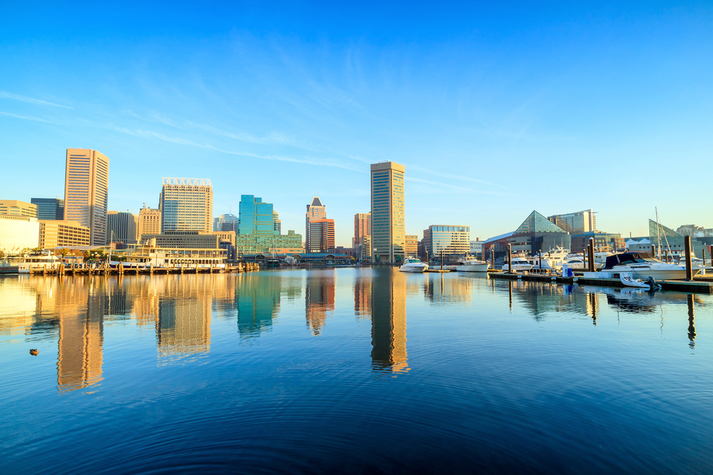 Skyline of tall buildings reflecting next to water in Baltimore