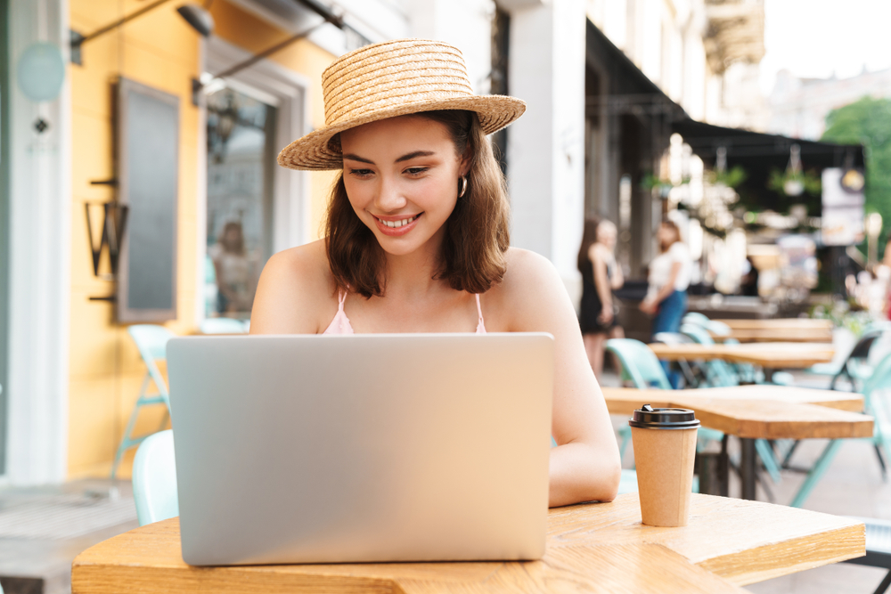 Young woman in European cafe working on laptop