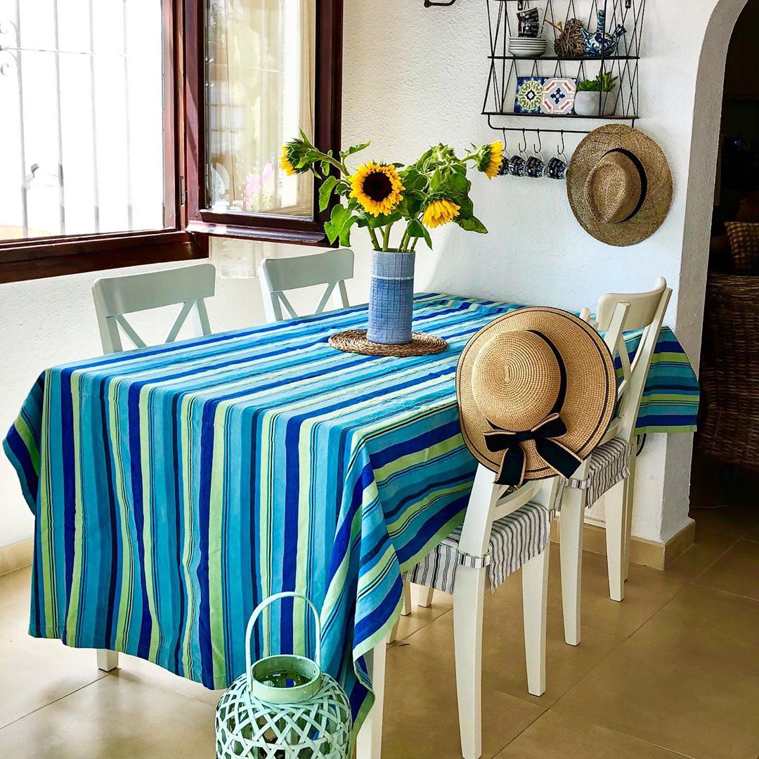 Table with blue table cloth and vase of yellow flowers. Photo by Instagram user @casasmoraira