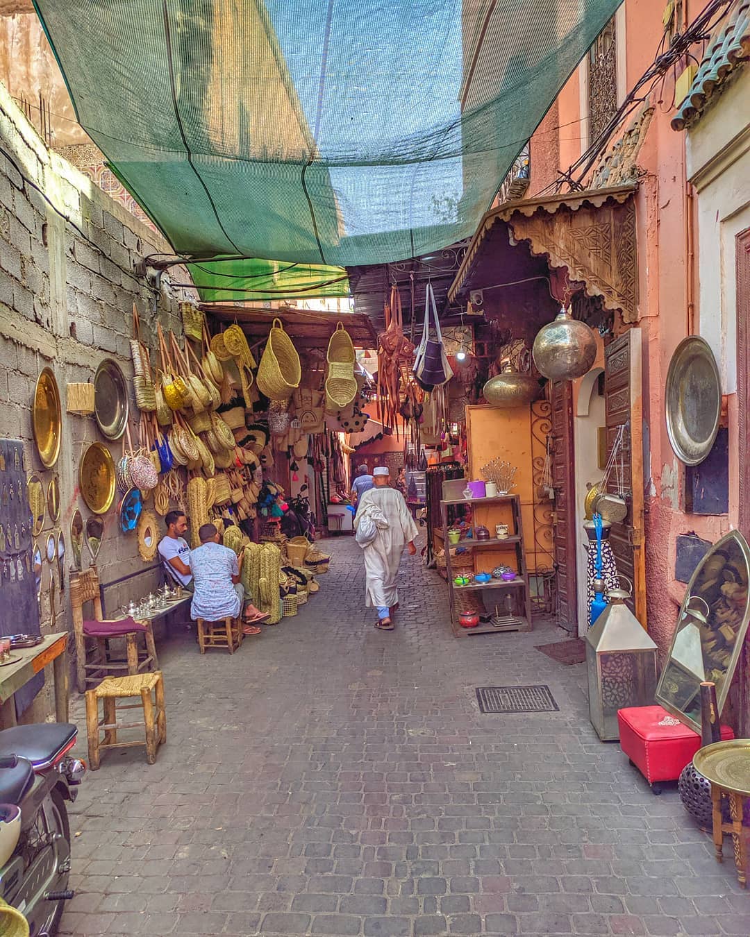 Guy walking through a market in Marrakech. Photo by Instagram user @nandoandre
