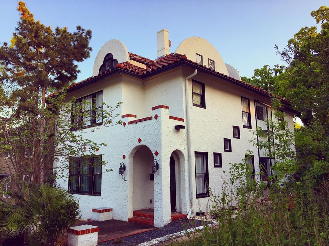 Two-story white house with red roof and trim. Photo by Instagram user @housesofhydeparkatx