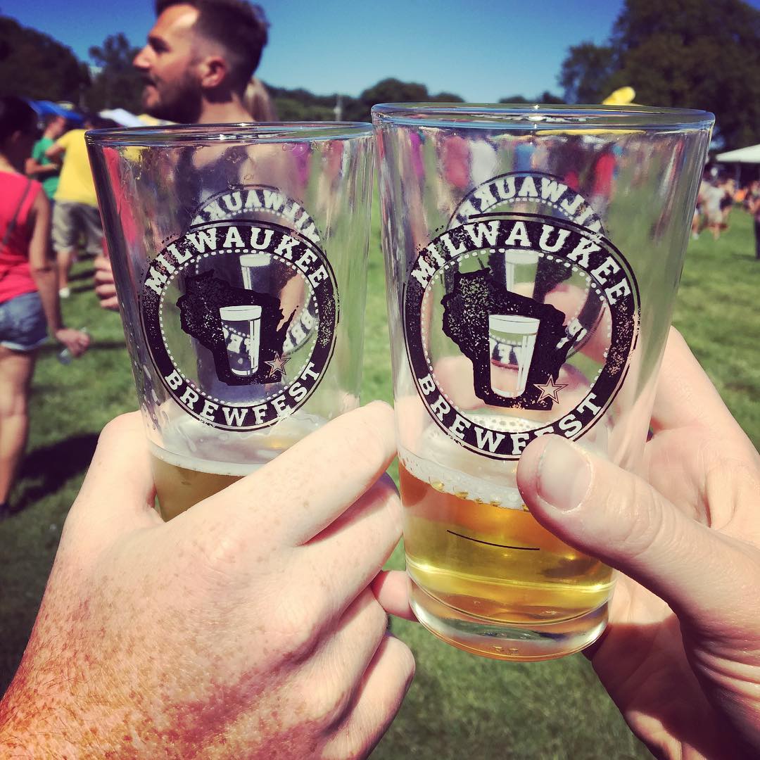 Two people holding up beer glasses at festival. Photo by Instagram user @milwaukeebrewfest