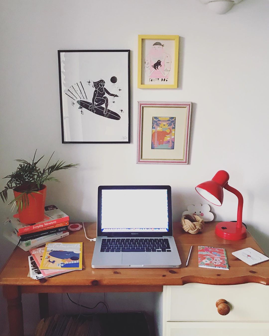 Computer on desk and colorful paintings on the wall. Photo by Instagram user @infalmouth