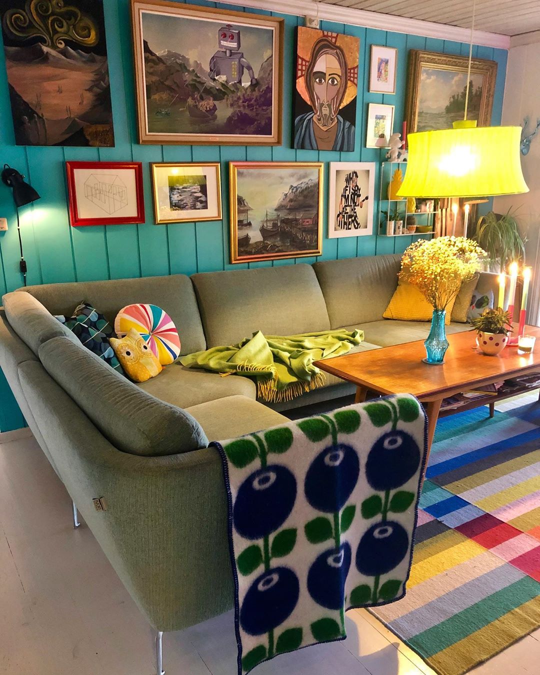 Blue living room with green couch and patterned blanket. Photo by Instagram user @polkadotgrid