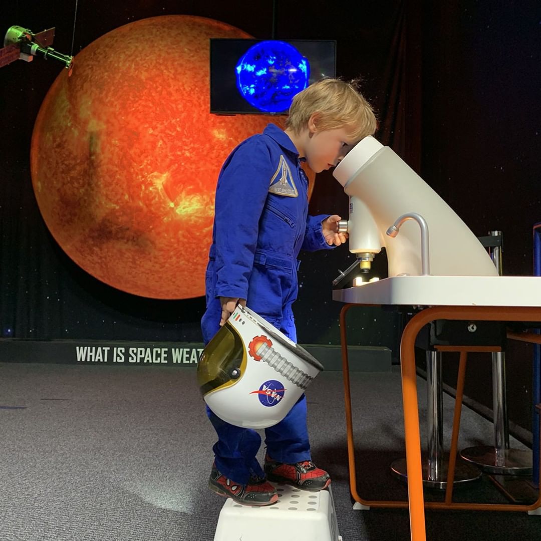 Little boy looking into a telescope in space outfit. Photo by Instagram use @spacefoundation