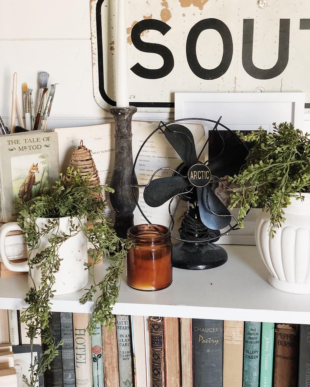 Vintage fan and vase on a bookshelf. Photo by Instagram user @keeleymckendree