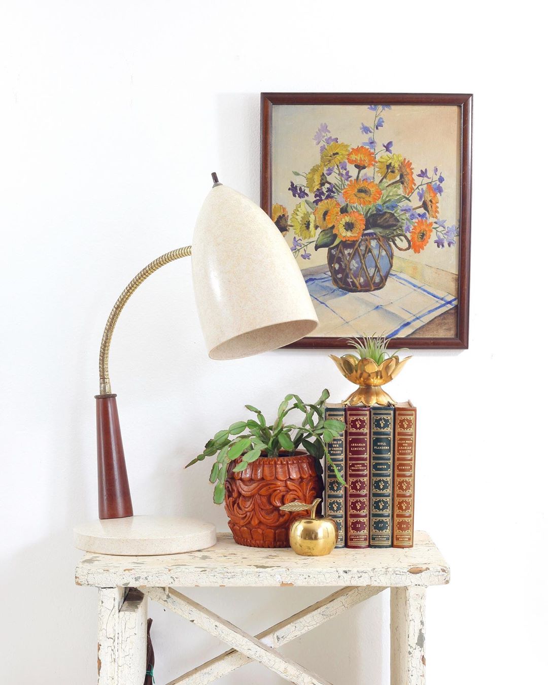 White vintage table with books and lamp on it. Photo by Instagram use @wiseapplevintage
