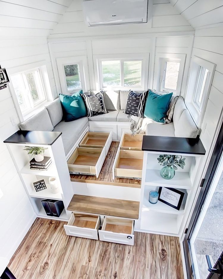 Living room seating with storage drawers under couch and raised floor. Photo via Instagram user @moderntinyliving