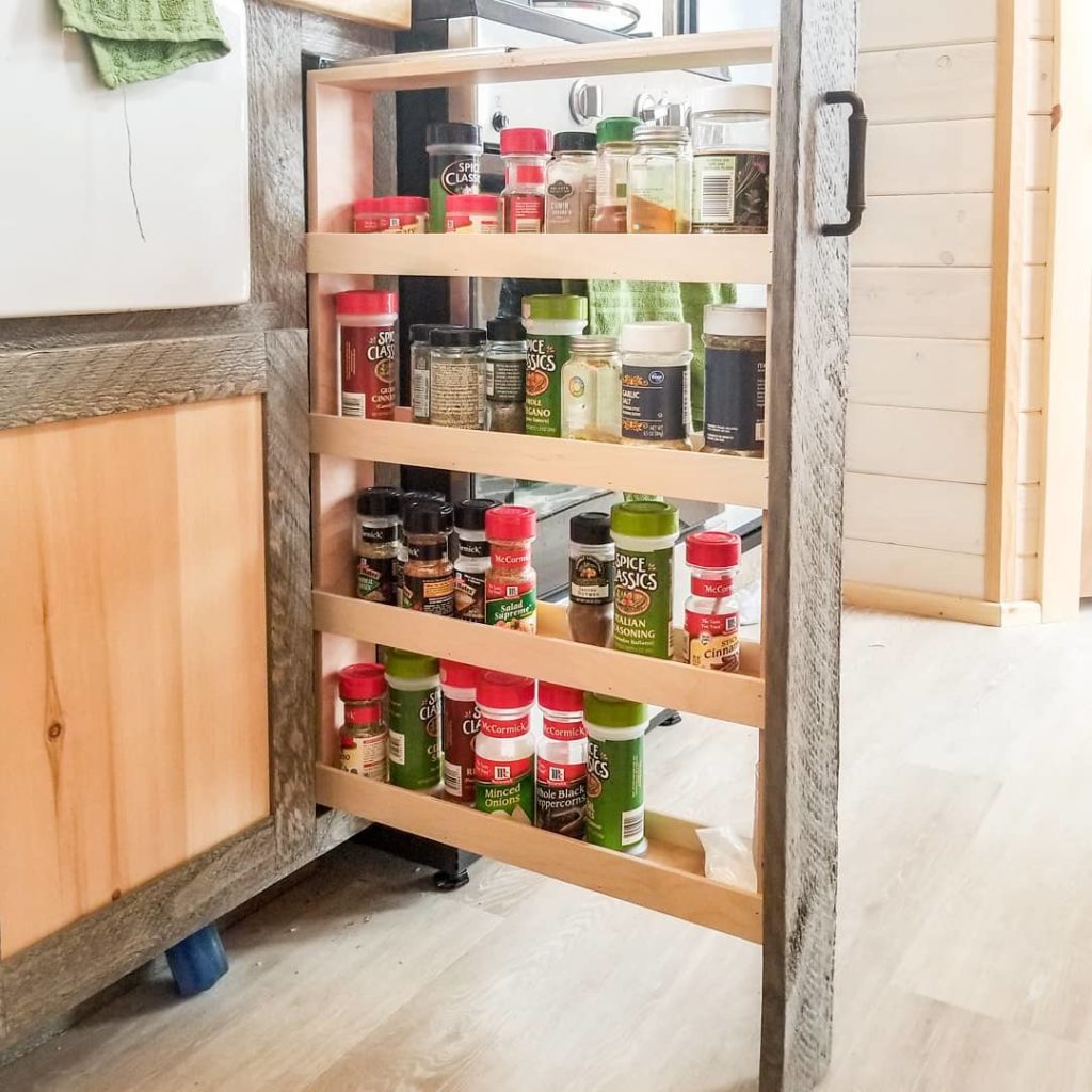 A pull-out spice rack offers easy access to cooking essentials. Tuck a narrow rack on wheels next to the fridge to use it as a pantry for dry goods. Fit toe-kick drawers between the bottom of your cabinets and the floor as a clever way to maximize space in a small kitchen. Or utilize behind-the-door storage like shoe organizers, hooks for bathroom towels, and pantry door organizers to declutter and organize loose items in your tiny house. Photo via Instagram user @heatherdhansen