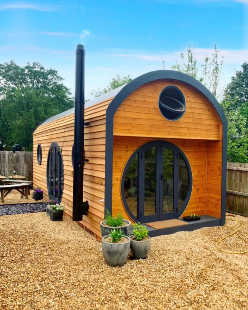 Exterior of a tiny house with round doors and windows. Photo by Instagram user @myshirehouses