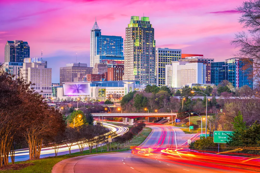 Tall buildings with lights on and pink sky.