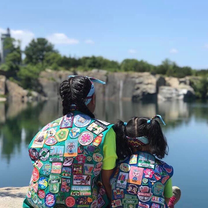 Two girls sitting on a rock wearing girl scouts vests. Photo by Instagram user @girlscouts
