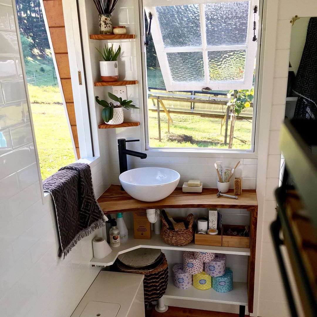 Tiny bathroom with windows open and shelves in the corner. Photo by Instagram user @little_things_tinyhouse