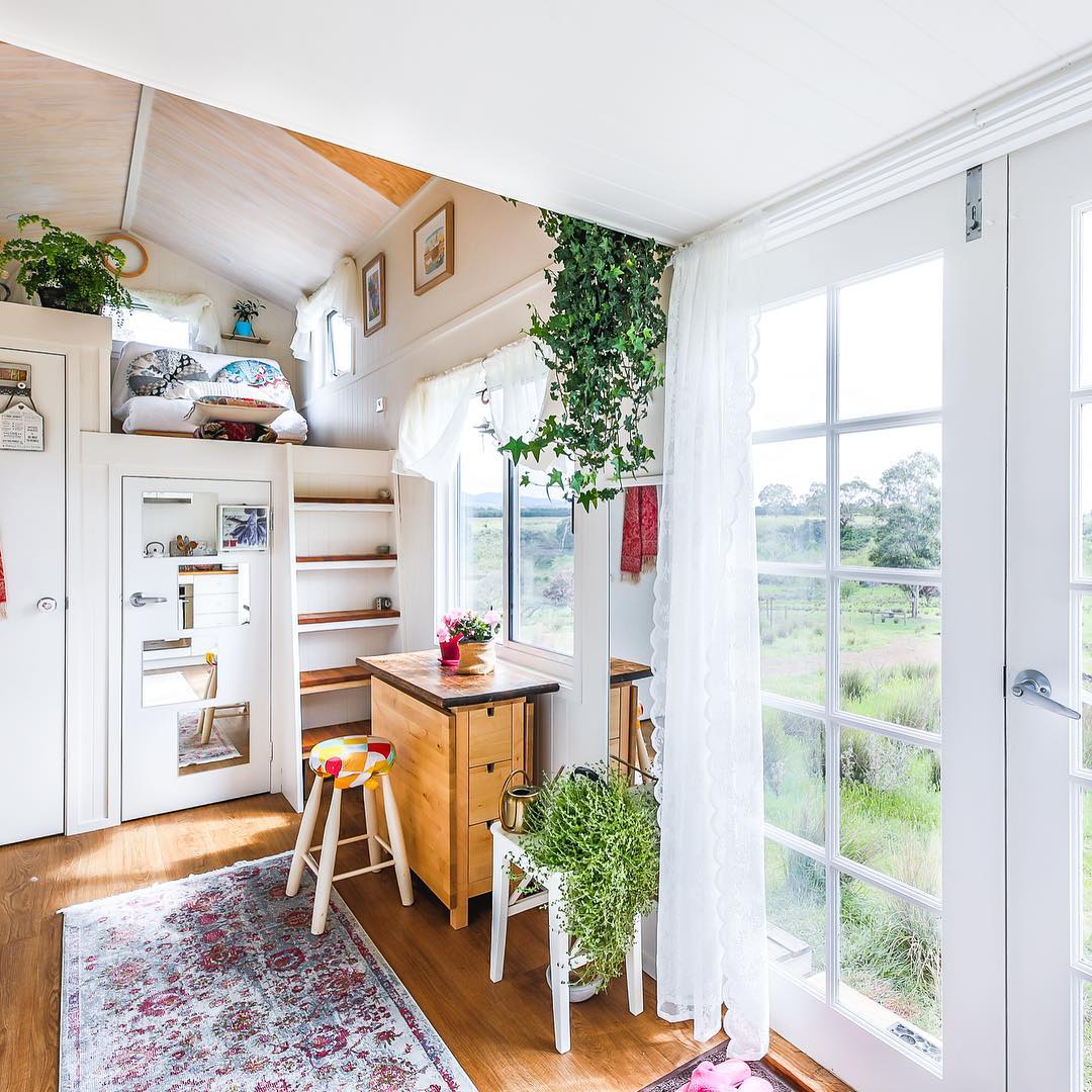 Tiny home living room with white walls and a gray rug. Photo by Instagram user @livingbiginatinyhouse