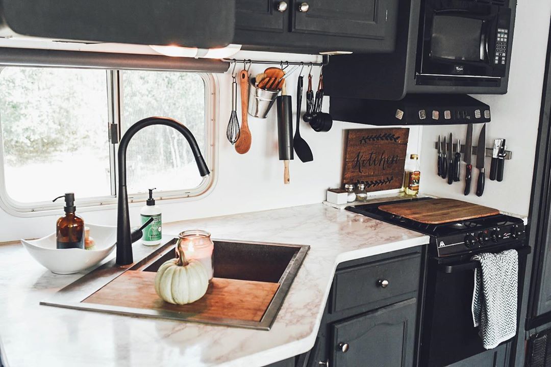 Tiny kitchen with black cabinets and hanging utensils. Photo by Instagram user @leahcboaz