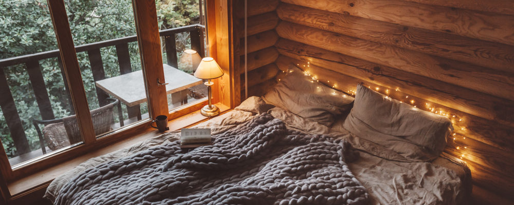 Bed with gray bedding and twinkle lights around it.