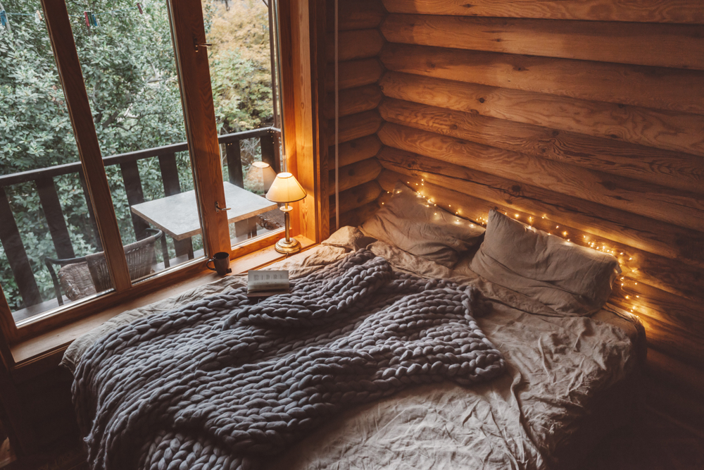 Bed with gray bedding and twinkle lights around it.