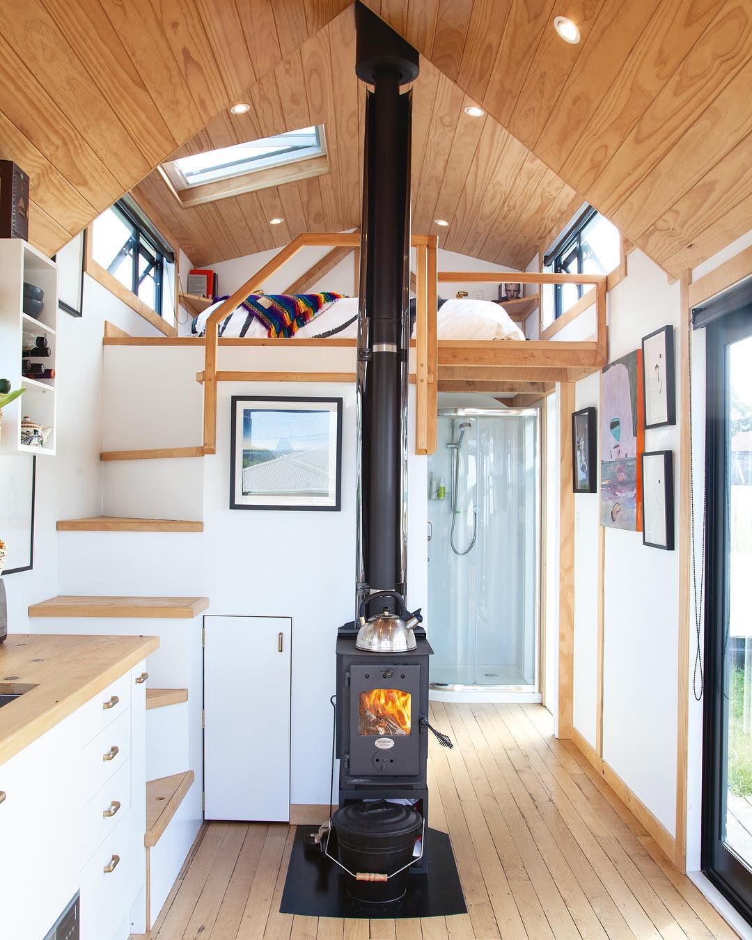 Tiny home with white walls and a black wood furnace. Photo by Instagram user @camandas_tinyhouse 