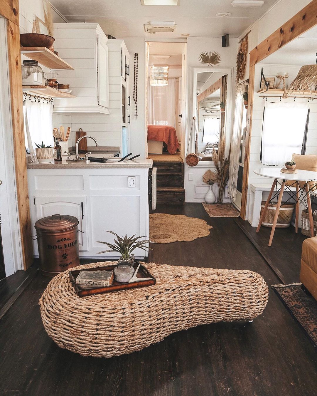 Tiny home with white walls and wicker coffee table. Photo by Instagram user @shelbyadrift