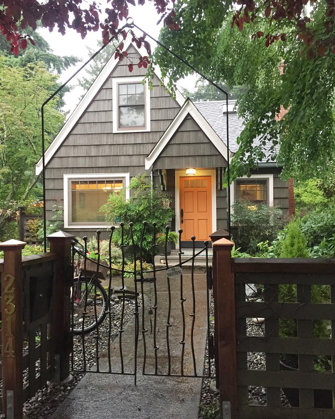 Gray house with white trim and wrought iron fence in front. Photo by Instagram user @kseniavasenev