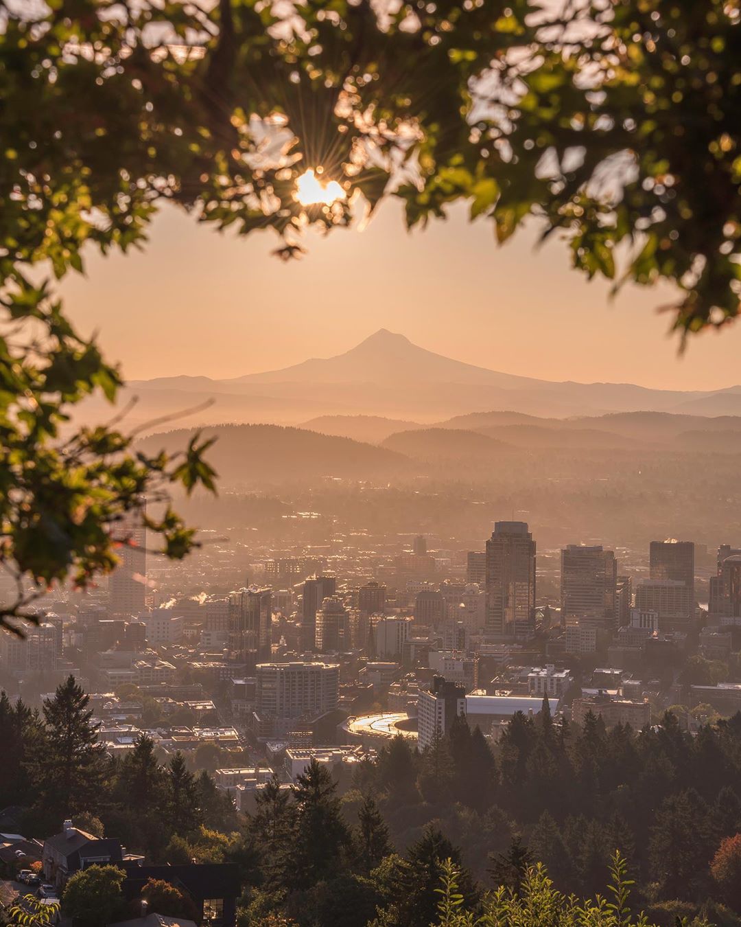 Skyline of tall buildings and mountains during sun rise in Portland, OR. Photo by Instagram user @50shadesofpnw