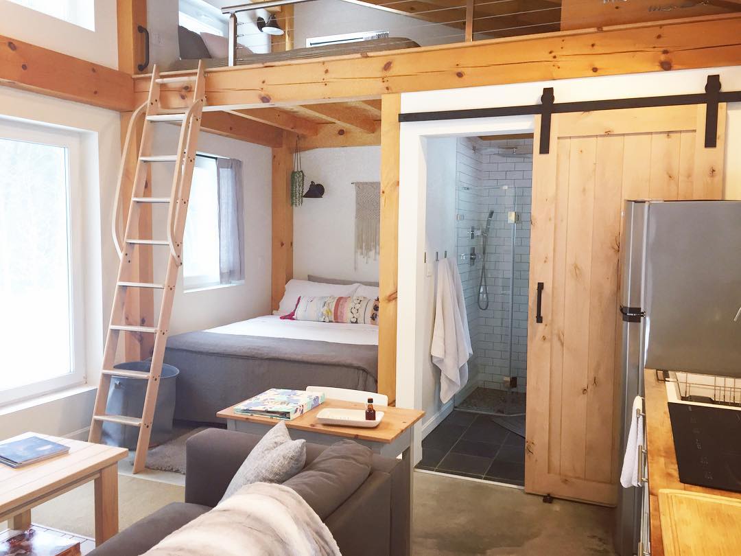 Tiny home bed and bathroom with wood walls. Photo by Instagram user @honeycrisp_cottage