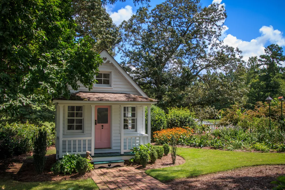 Tan tiny home between trees on a sunny day