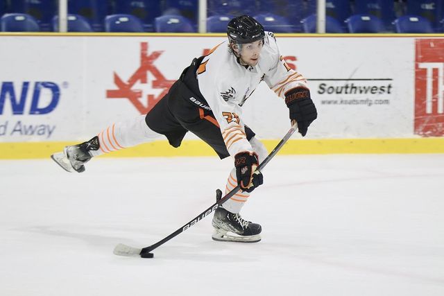 A hockey player hitting the puck on the ice rink while looking ahead. @el_paso_rhinos