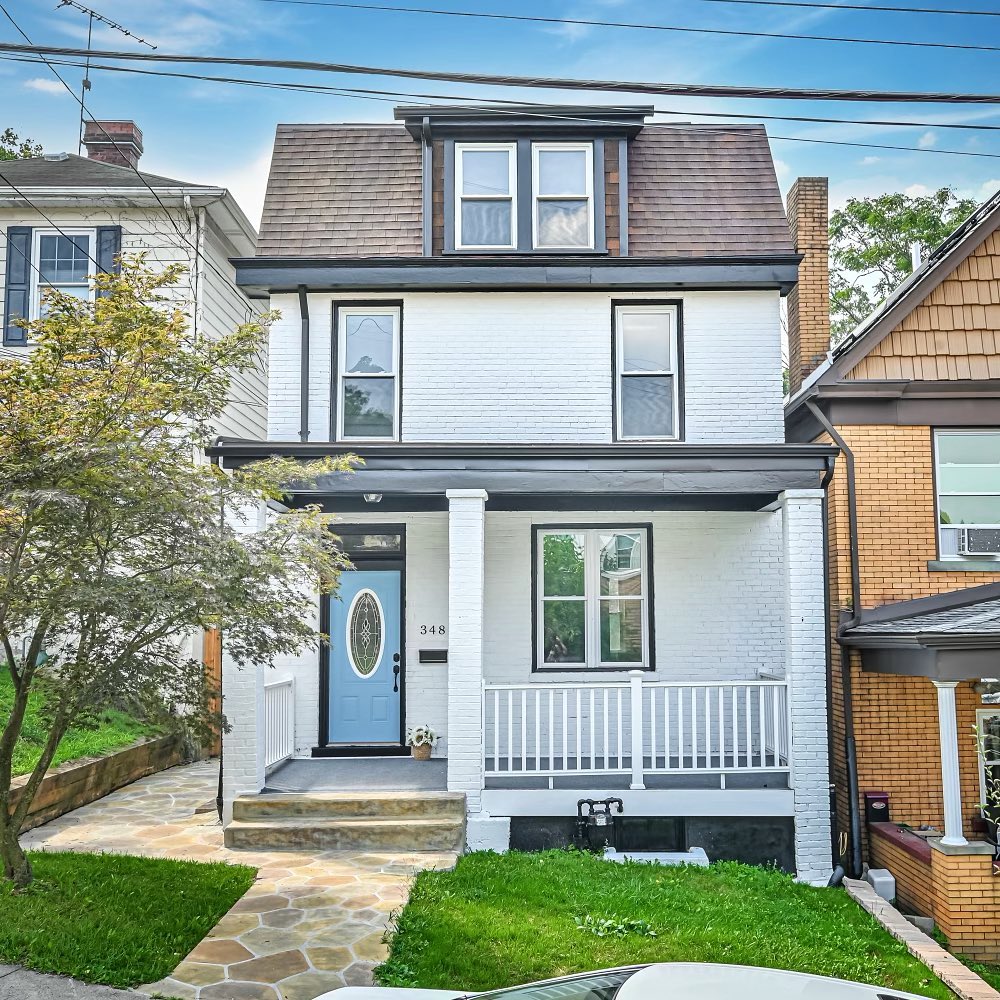 White brick two story home with light blue door. Photo by Instagram user @the_bethdanchekgroup