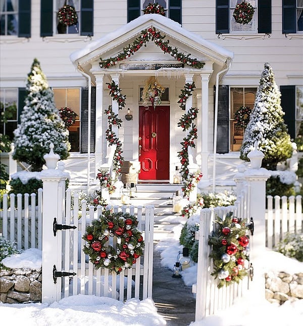 White house with red door covered in Christmas decor. Photo by Instagram user @greencottageideas