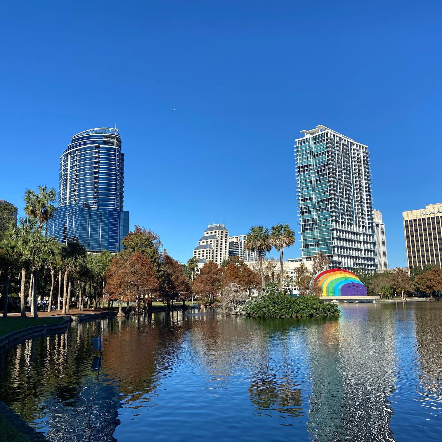 Cityscape of Orlando with buildings and sculptures situated around the water. 