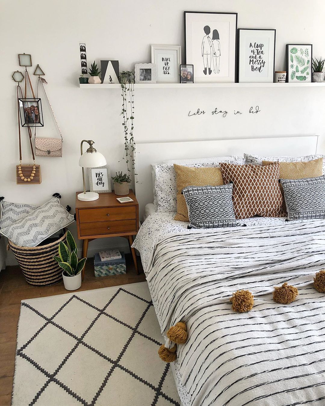 White bedroom with bed adorned in striped sheets and pictures on wall. Photo by Instagram user @nest_number_9